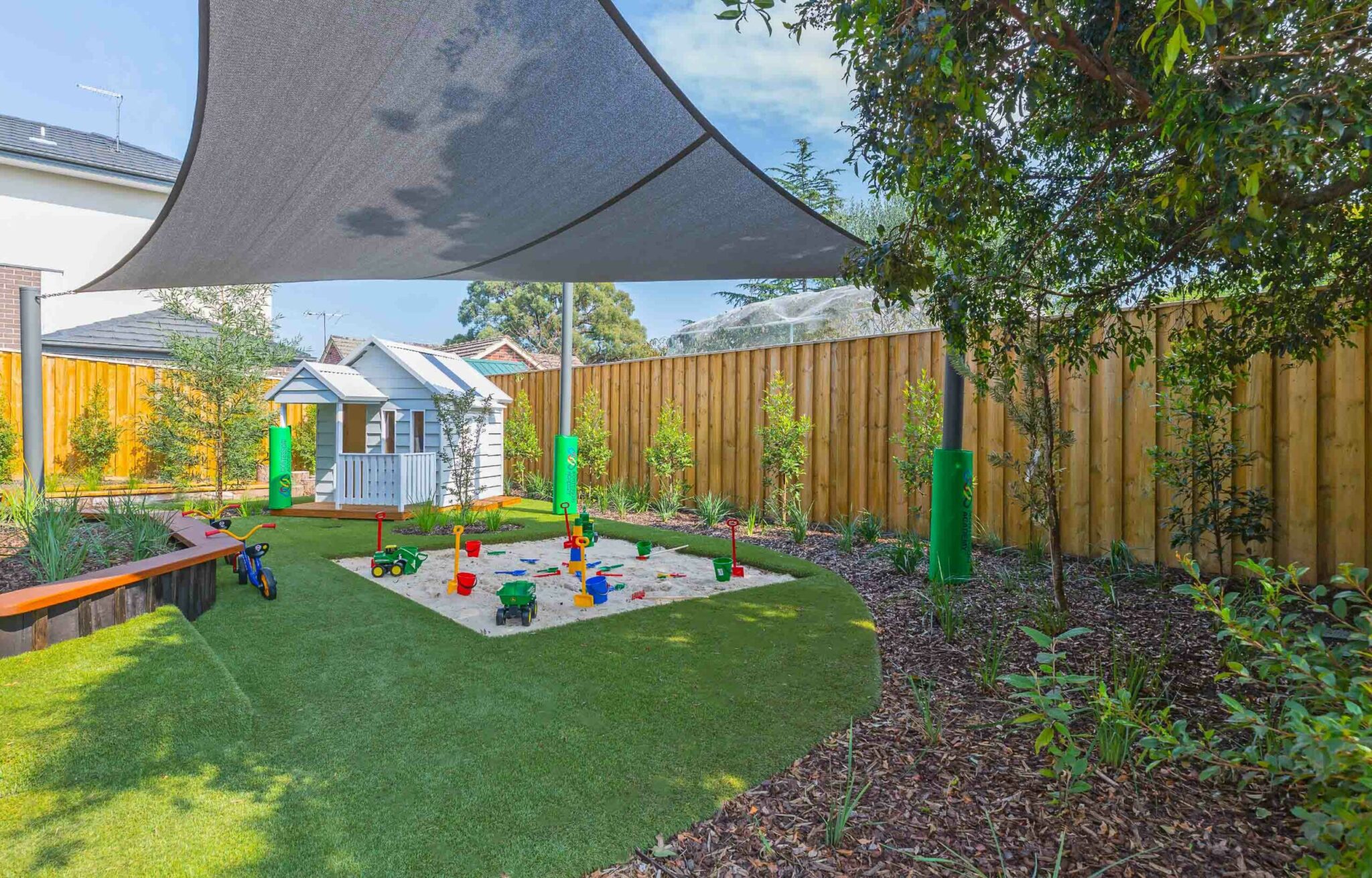 Childcare Outdoor Playground with white cubby house and sandpit