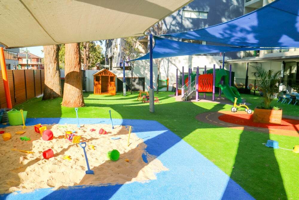 Outdoor playground at Montessori Academy’s Entrada childcare with a sandpit, playhouse, bike track and turfed play areas.