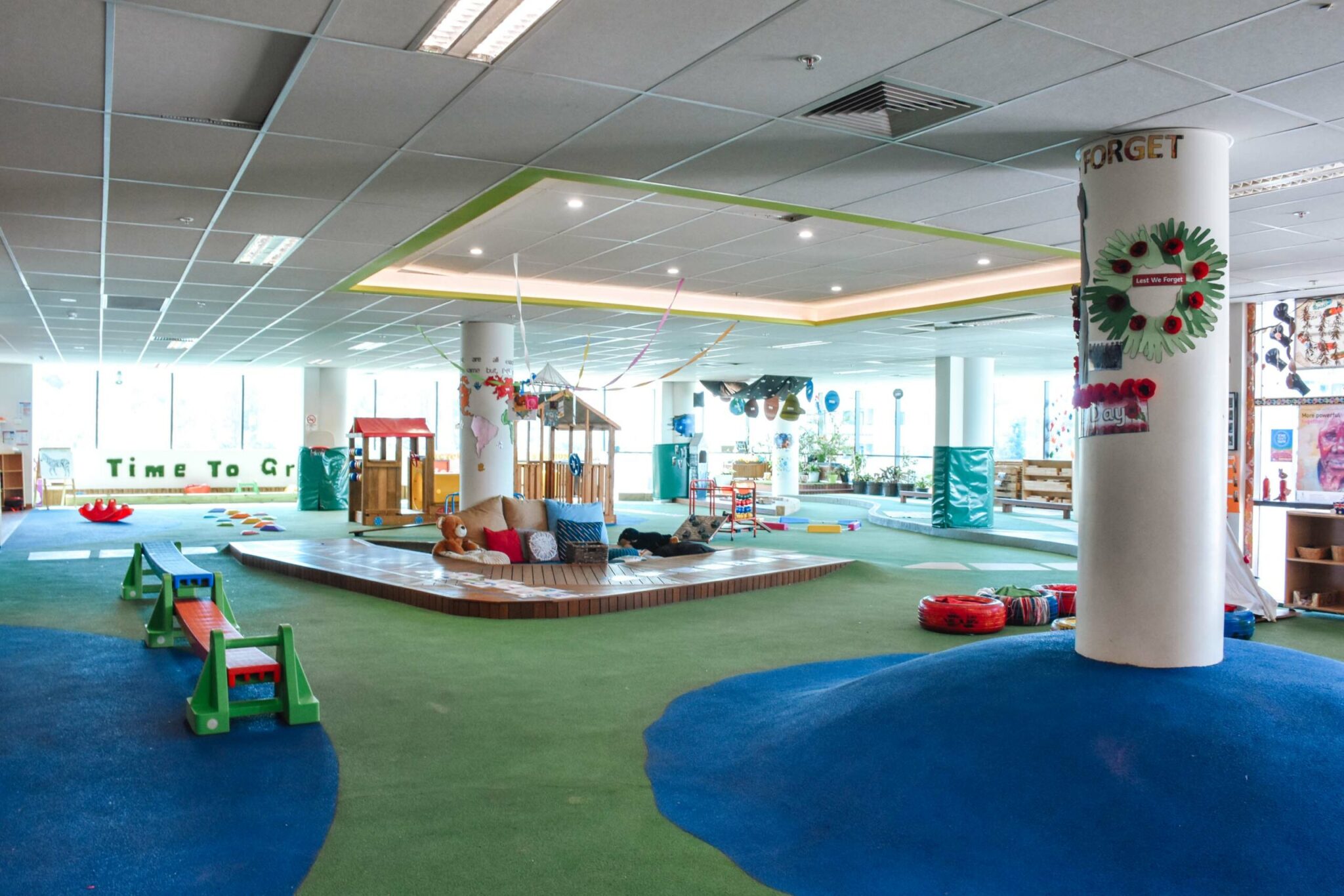 Large turfed indoor play area at Montessori Academy’s Bankstown daycare, with playhouses in the background.