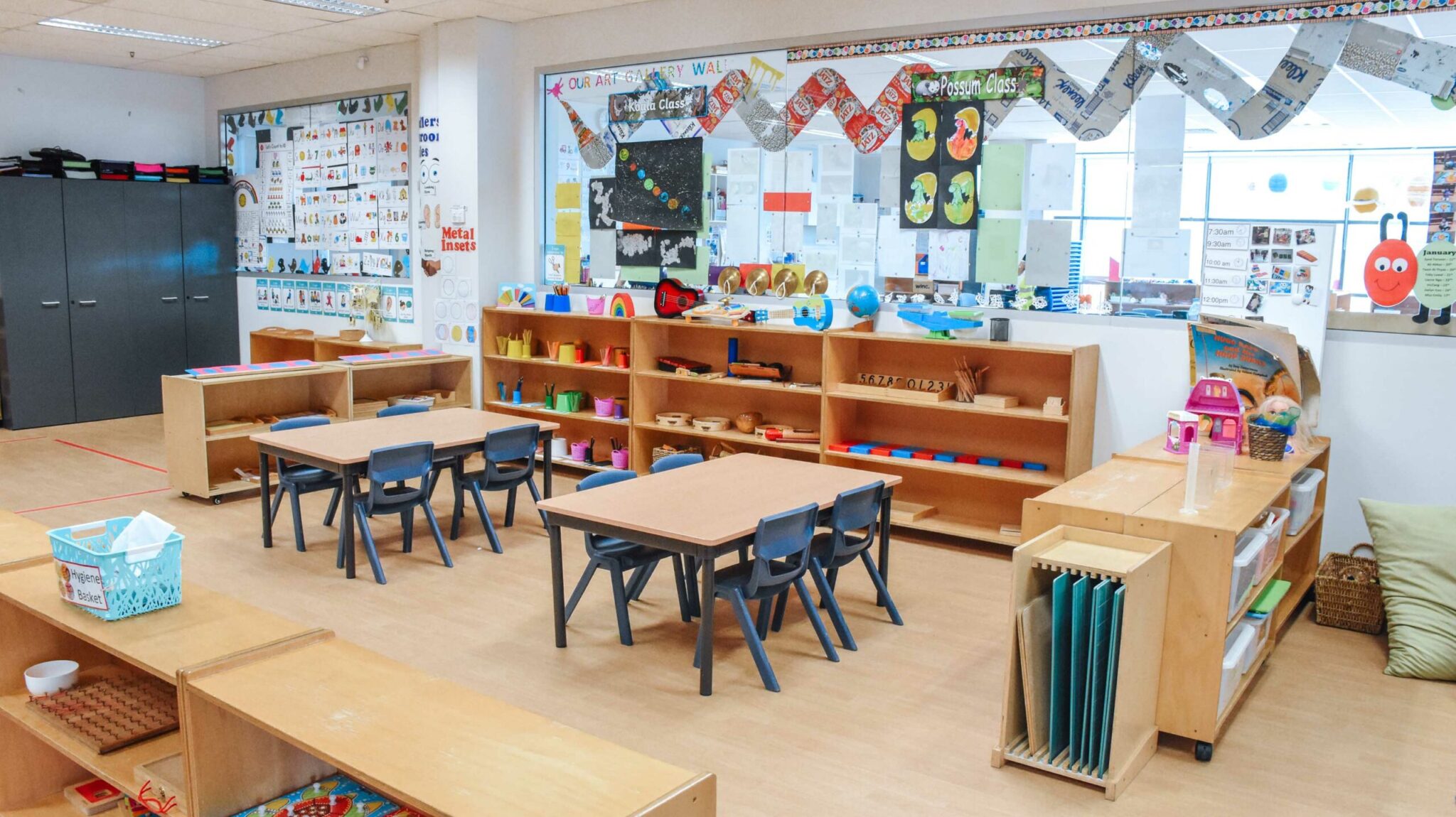 Classroom interior of Montessori Academy’s Bankstown daycare, with shelves of learning materials and paper cutouts on walls.
