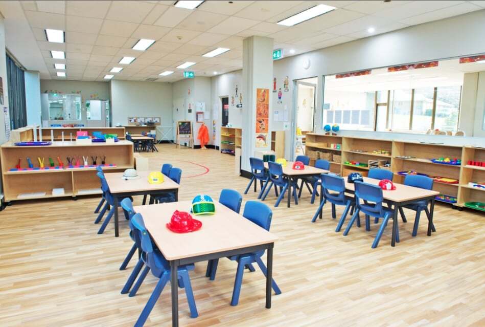 Classroom interior with children’s tables and spacious shelves with learning materials at Macquarie Park Montessori Academy.