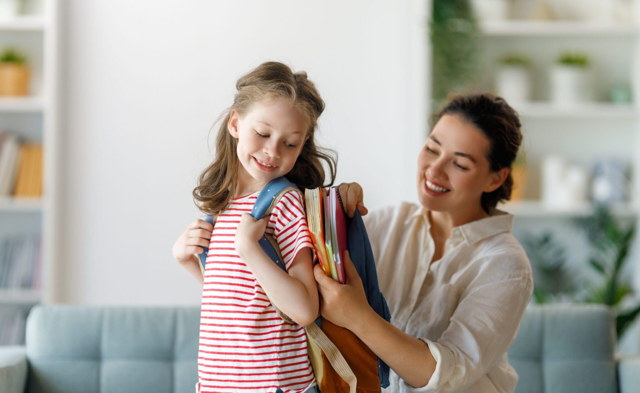 Woman help pack a child's backpack, ready for school