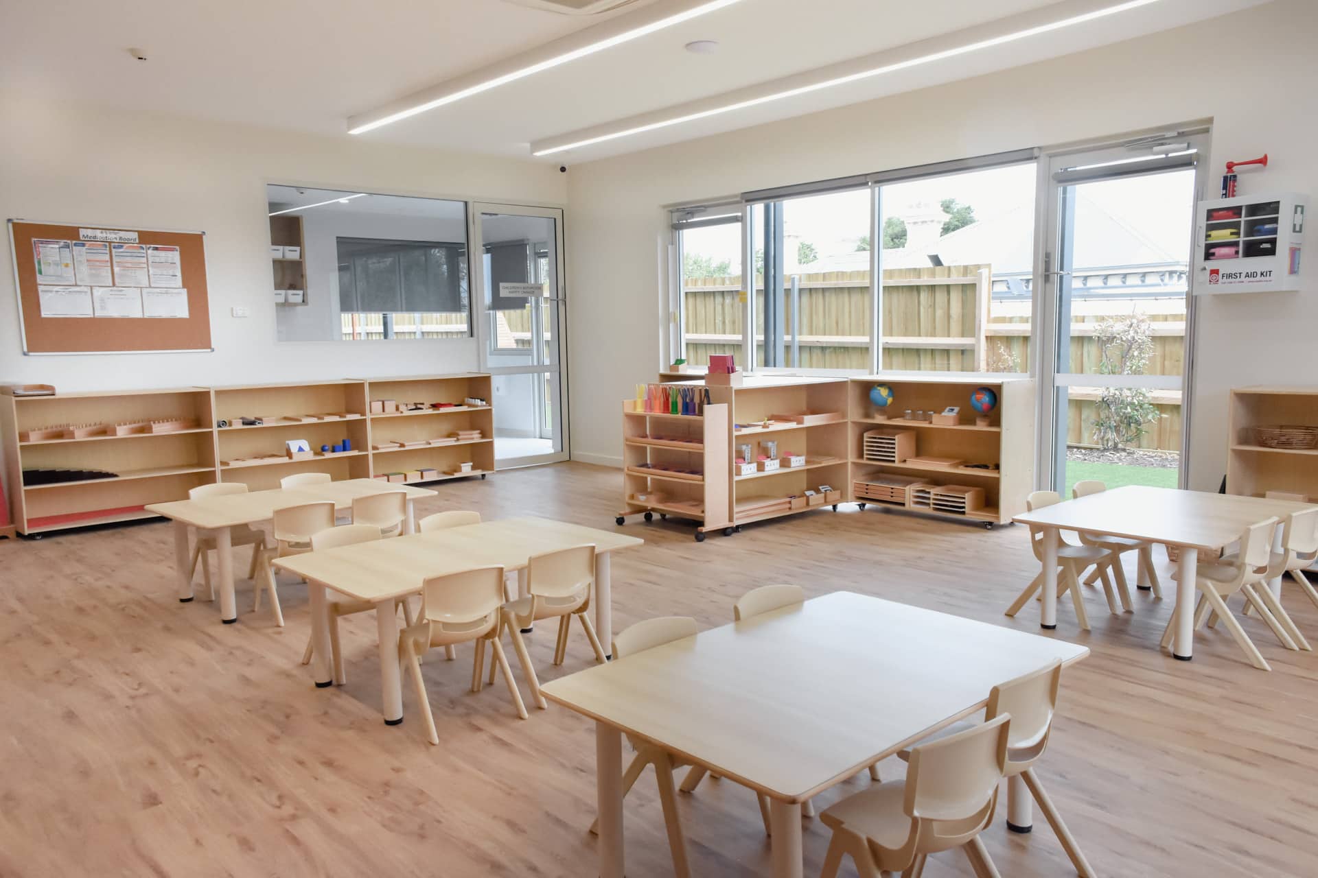 Classroom interior of Montessori Academy’s Elsternwick childcare, with educational materials on shelves and small tables.