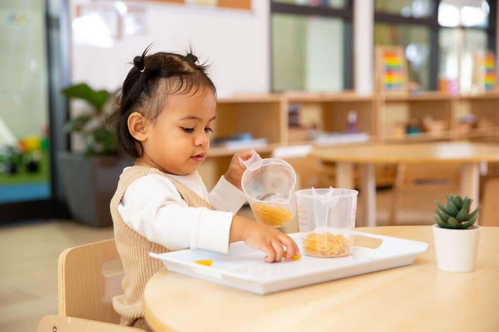 Montessori Infant engaged in practical life activity in nursery classroom for ages 0-2