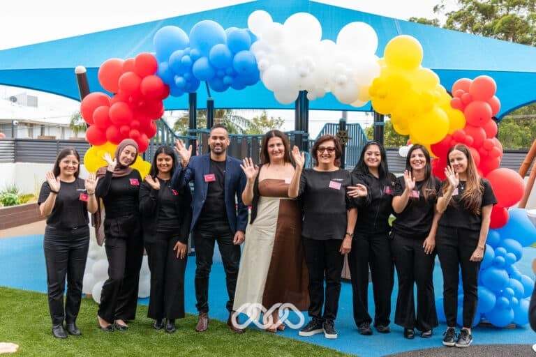 Riverwood Montessori Academy team stand under colourful balloon arch to celebrate grand opening event