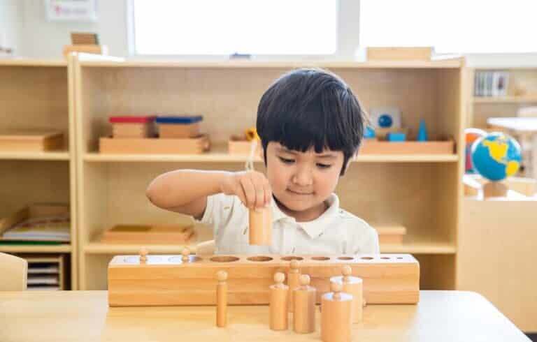 Montessori Toddler working with Cylinder Blocks in Toddler Classroom