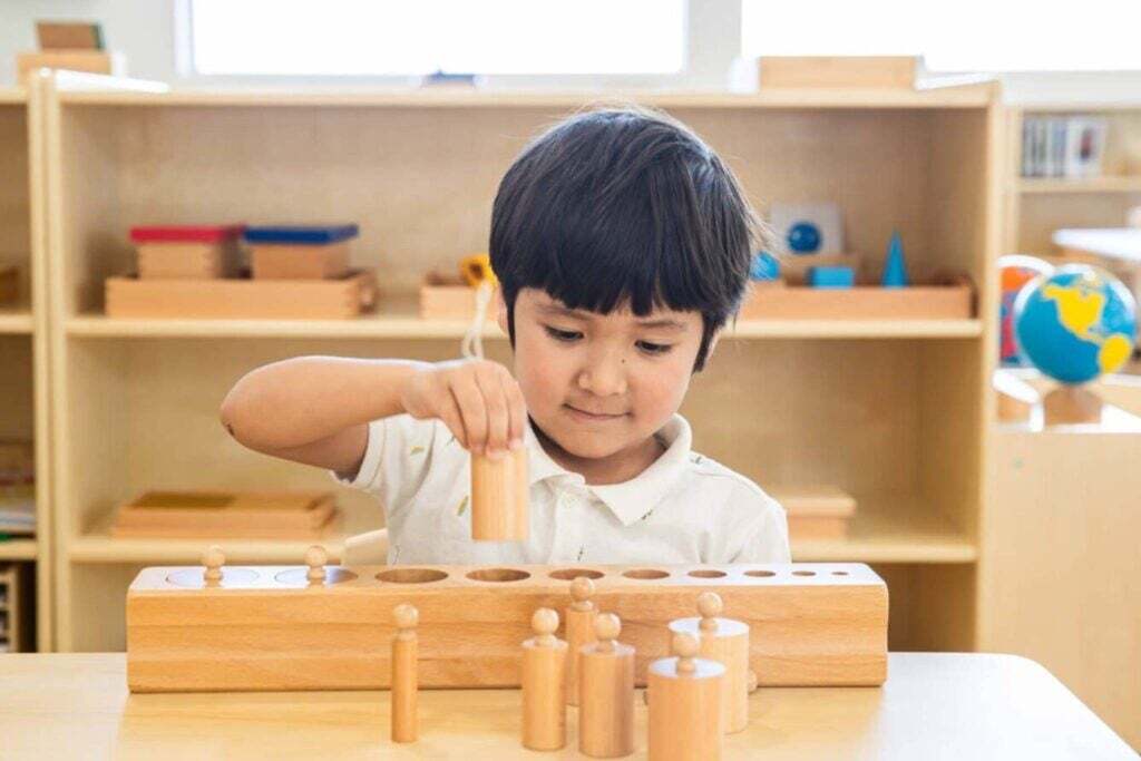 Montessori Toddler working with Cylinder Blocks in Toddler Classroom